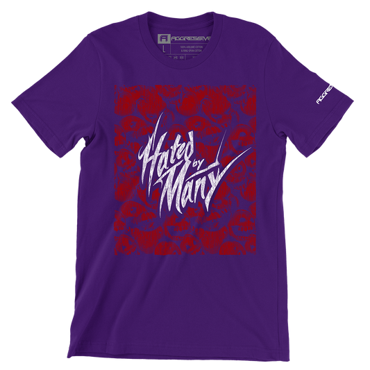 purple t-shirt features the defiant phrase "Hated by Many" in sharp, distressed white typography that stands out dramatically against a deep red background patterned with stylized skulls